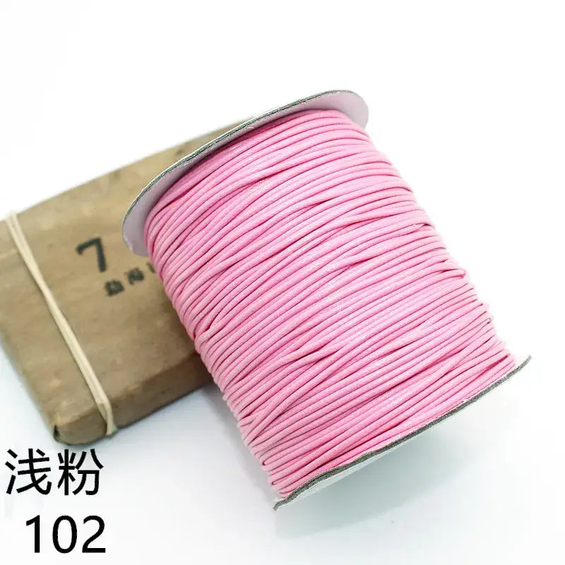 Gros plan sur une bobine de fil rose à côté d’une boîte pour le bracelet personnalisé de photos d’animaux