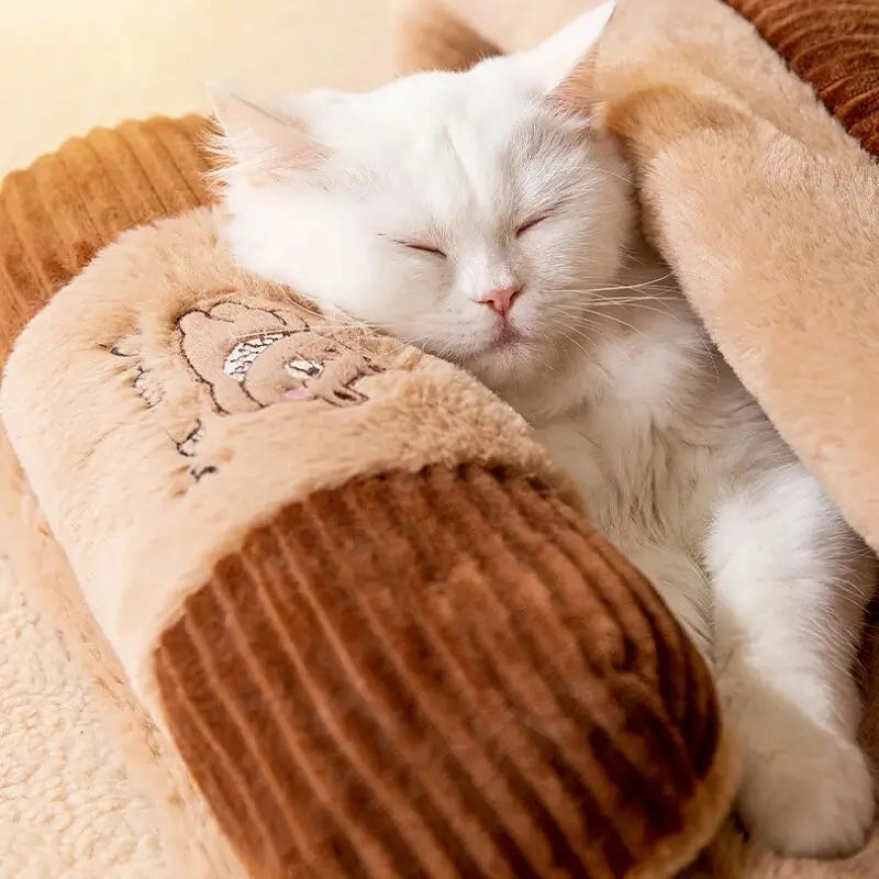 Chat blanc confortablement endormi sur une couverture marron dans le Cozy Winter Cat Bed, parfait pour le couchage